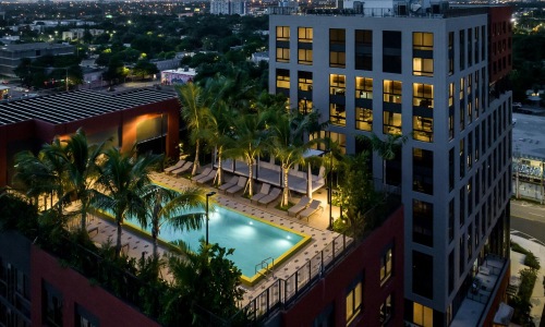 a building with a pool and trees in front of it